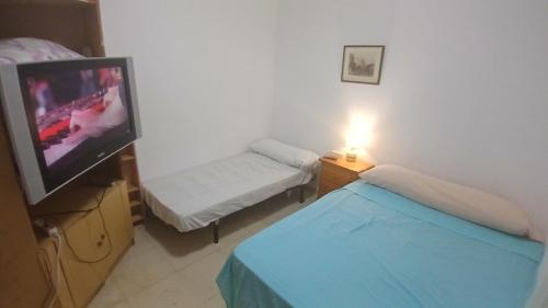 une petite pièce avec une télévision, un lit et une table dans l'établissement Habitacion Privada 2 Personas Toledo, à Tolède