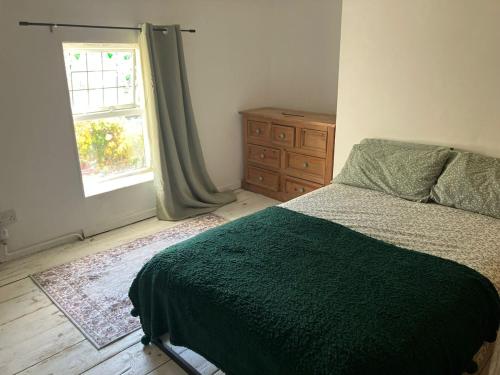 a bedroom with a bed and a window and a dresser at Nant caer Efail Cottage - Stream by the forge in Pen-y-cae