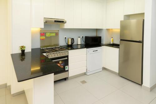 a kitchen with white cabinets and a stainless steel refrigerator at New Large 2BR Apt Sleeps 10 Adults with Pool Gym Parking and Wifi in Dubai