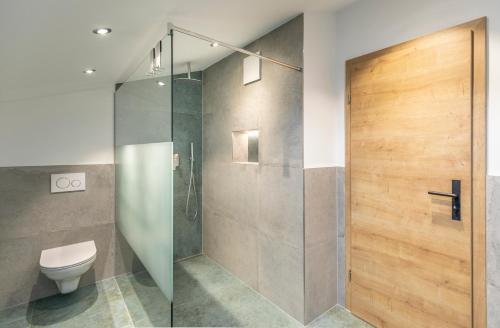 a bathroom with a shower and a toilet and a glass door at Gästehaus zum Thoma in Kreuth