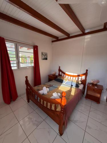 a bedroom with a wooden bed with red curtains at Villa Nanou , Haut de villa calme et petite vue sur Mer in Bouillante