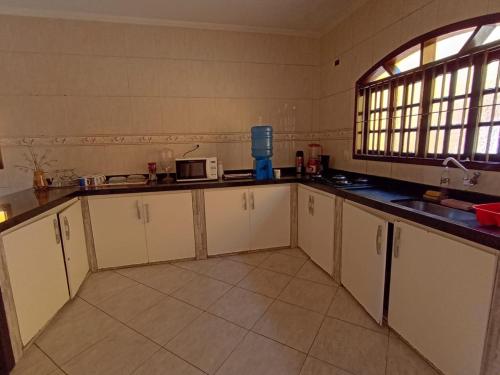 a kitchen with white cabinets and a window at Haja Luz Casa Pousada 1 em Itaquaquecetuba in Itaquaquecetuba
