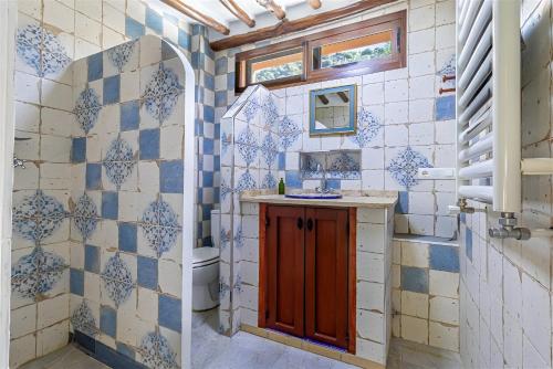 a bathroom with blue and white tiled walls and a toilet at Aguas Calmas in Nigüelas