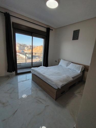 a bedroom with a bed and a large window at Brand new apartment in Sport city Tangier in Tangier