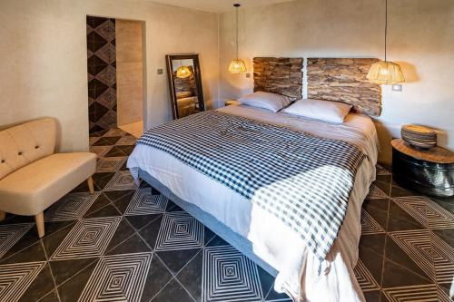 ein Schlafzimmer mit einem großen Bett und einem Stuhl in der Unterkunft Les Terrasses de MAJORAC - Le Cottage in Bozouls
