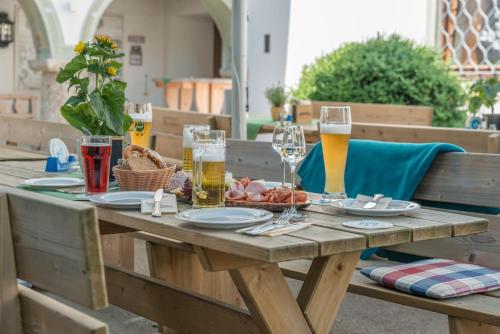 a wooden table with plates of food and glasses of beer at Hotel Alter Wirt in Weyarn