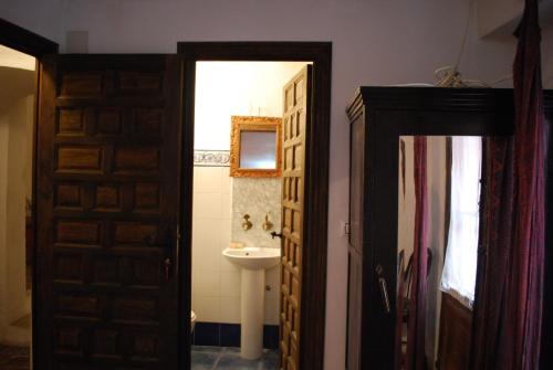 a bathroom with a sink and a mirror and a door at Fonda Del Tozal in Teruel