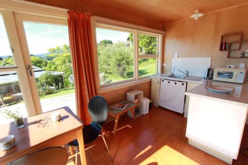 cocina con mesa y sillas y ventana grande en Estuary View - Peaceful Onekaka Retreat, en Onekaka