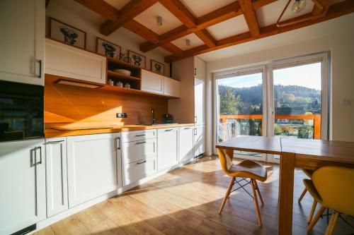 eine Küche mit einem Tisch und einem großen Fenster in der Unterkunft HARLEY FAMILY APARTAMENT in Muszyna