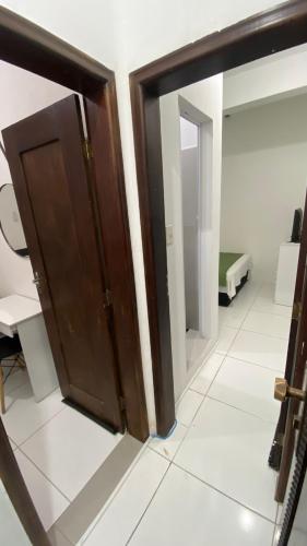 een houten deur in een kamer met een spiegel bij Suíte Standard Privado in Vitória