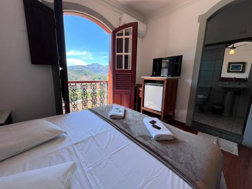 a bedroom with a large bed and a balcony at Pousada Casa dos Contos in Ouro Preto