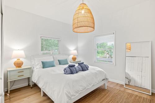 ein Schlafzimmer mit einem weißen Bett mit blauen Kissen darauf in der Unterkunft Casa Madeore Luxury Bungalow in St. Augustine
