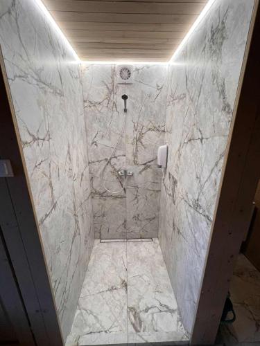 a bathroom with a walk in shower with marble tiles at Pas Rimute in Zapyškis