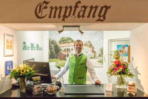 a man standing at a counter with a computer at Hotel Alter Wirt in Weyarn