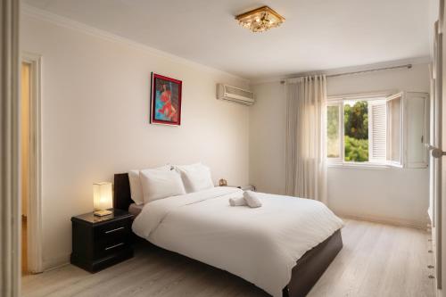 a white bedroom with a large bed and a window at The White Coconut Stay in Cairo