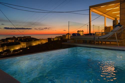 a swimming pool with a sunset in the background at Villa D' Republic Dubrovnik - Infinity Pool & Old Town Views in Dubrovnik