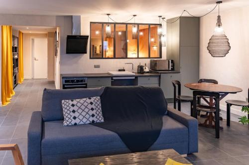 ein Wohnzimmer mit Sofa und eine Küche in der Unterkunft Les Terrasses de MAJORAC - La Grange in Bozouls