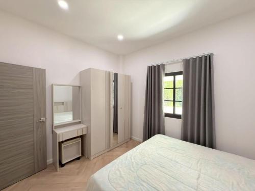 a bedroom with a bed and a dresser and a mirror at Tropical home close to nature and city in Ban Mai I