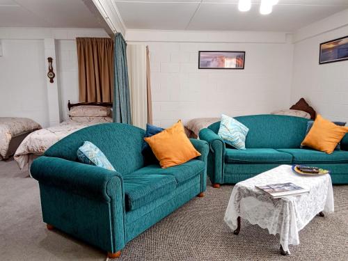 ein Wohnzimmer mit zwei blauen Sofas und einem Bett in der Unterkunft Park View 'Home Away From Home' in Feilding