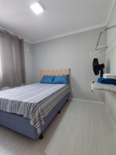 a small bedroom with a bed with a blue pillow at Apartamento aconchegante e tranquilo Suzano in Suzano