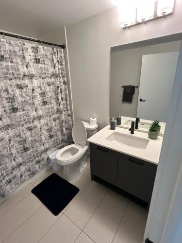 a bathroom with a toilet and a sink and a mirror at Vibrant 1 Bedroom Condo Apt in Toronto