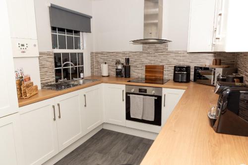 een keuken met witte kasten en een aanrechtblad bij The Terminus Loft in Conisbrough