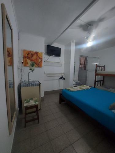 a bedroom with a blue bed and a tv on the wall at Pousada Formosa in Porto Seguro