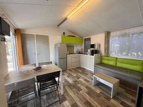 un salon avec un canapé vert et une table dans l'établissement Mobile Home Camping Paradis, à Trédrez