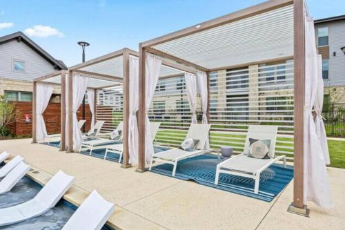 Un patio con sillas blancas y un cenador. en A plus location pool washer dryer gym modern, en Sherman