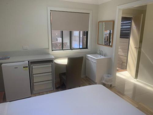 eine Küche mit einem Waschbecken, einem Tisch und einem Fenster in der Unterkunft T's Resort & Motel in Port Macquarie