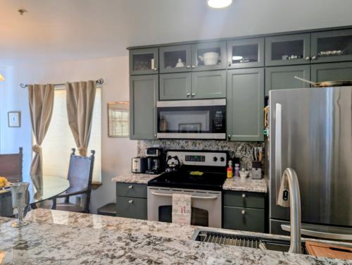 eine Küche mit grünen Schränken und einem Kühlschrank aus Edelstahl in der Unterkunft Peaceful Sunny Ski Out Ski In Condo, Parking, Pets in Telluride