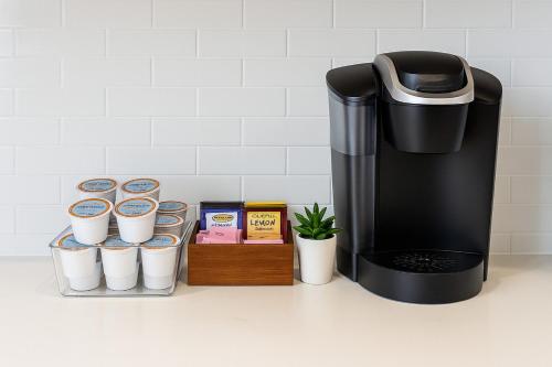 a coffee maker and cups on a counter at Cozy apartment by Pecan Park Texoma Med & More in Sherman