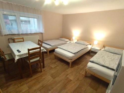 Cette chambre comprend 3 lits, une table et des chaises. dans l'établissement U Petra Hronec, à Hronec