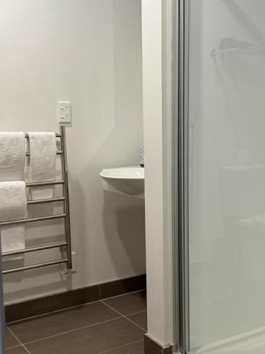 a bathroom with a shower and a sink and towels at Quest Henderson, Auckland Apartment Hotel in Auckland