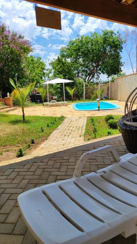 a white bench sitting on a patio next to a pool at Chalés Chácara Santa Felicidade 2 in Olímpia