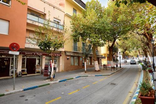 een lege straat in een stad met bomen en gebouwen bij Apartamento vital centrico in Lanjarón