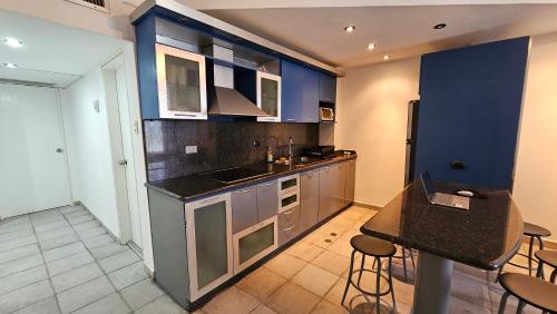 a kitchen with blue walls and counters and stools at Moderno Apartamento con Vista al Mar y Piscina in Boca de Aroa