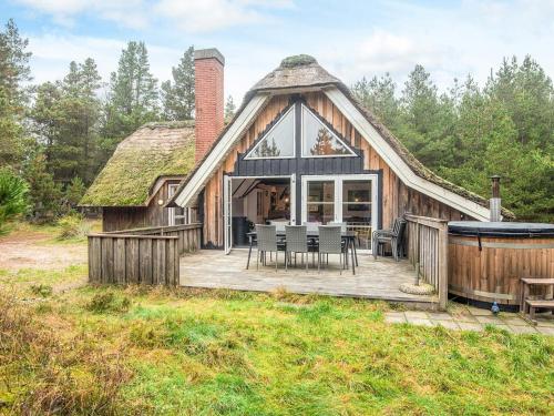 a log home with a thatched roof and a deck at Luxury Retreat in Blavand in Blåvand