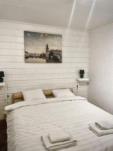 a bedroom with a white bed with a picture on the wall at Guesthouse Olivier in Hammarstrand