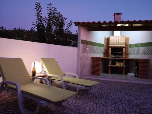 two chairs sitting on a patio with a fireplace at Quiaios Beach House in Quiaios