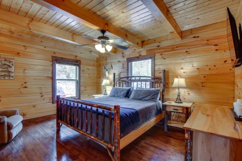 ein Schlafzimmer mit einem Bett in einer Blockhütte in der Unterkunft Serenity Now Cabin with Fire Pit and Game Room! in Logan