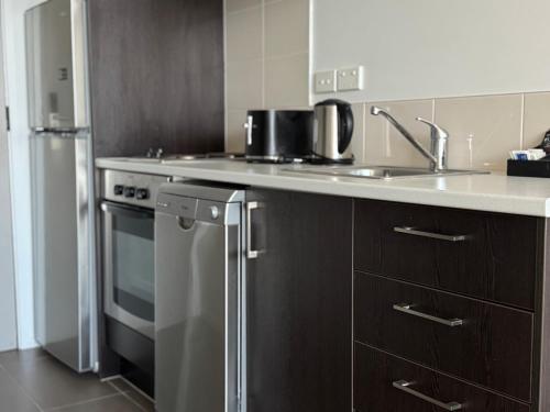 una cocina con fregadero y refrigerador en Quest Henderson, Auckland Apartment Hotel, en Auckland
