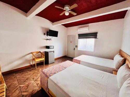 een slaapkamer met twee bedden en een plafondventilator bij Casa Gubidxa in Oaxaca City