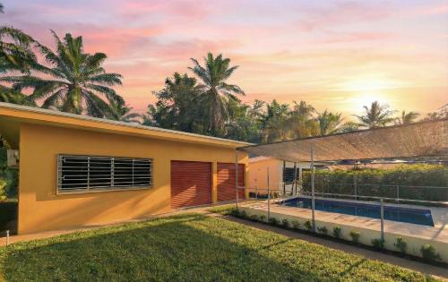 a house with a pool and palm trees at Pura Vida - Villa Lisa in Parrita