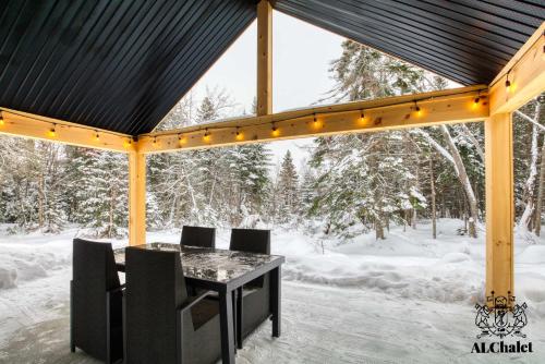 einen Pavillon mit einem Tisch und Stühlen im Schnee in der Unterkunft Cocotte d'hiver - Chalereux avec Foyer intérieur in Petite-Rivière-Saint-François