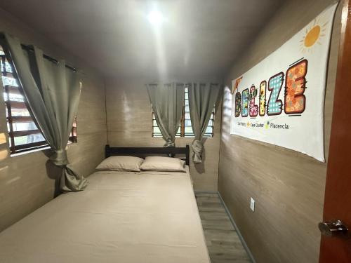 Una cama pequeña en una habitación pequeña con cortinas. en Delva's Villa, en Ciudad de Belice