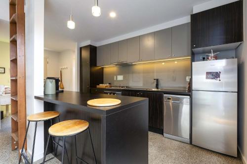 eine Küche mit einer Theke mit Hockern und einem Kühlschrank in der Unterkunft Spacious 1-Bed Townhouse in Norlane in Norlane