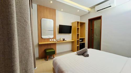 una habitación de hotel con una cama y un televisor en Mahesa Seminyak, en Seminyak