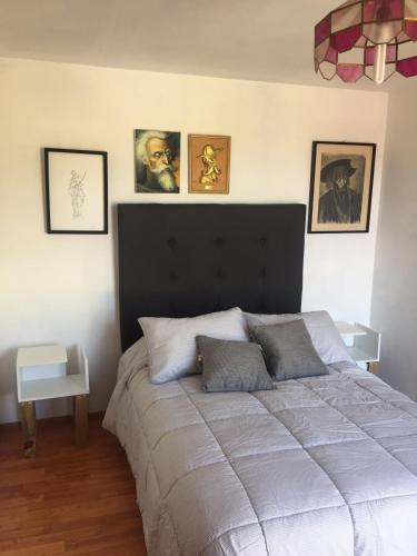 a bedroom with a large bed with four pictures on the wall at Casa Dos Hermanas in Guanajuato