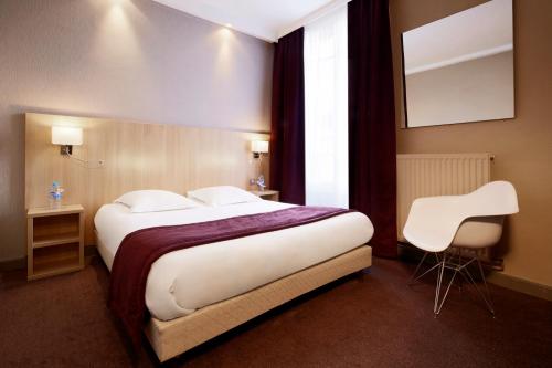 a bedroom with a large bed and two white chairs at Hôtel Europe and Spa in Reims